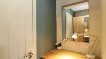 Un baño con tocador de madera, un espejo, una lámpara de pared y una planta en maceta.