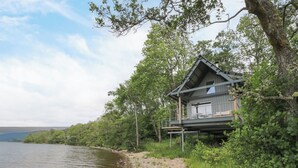 A lakeside cabin with a deck and outdoor seating area.