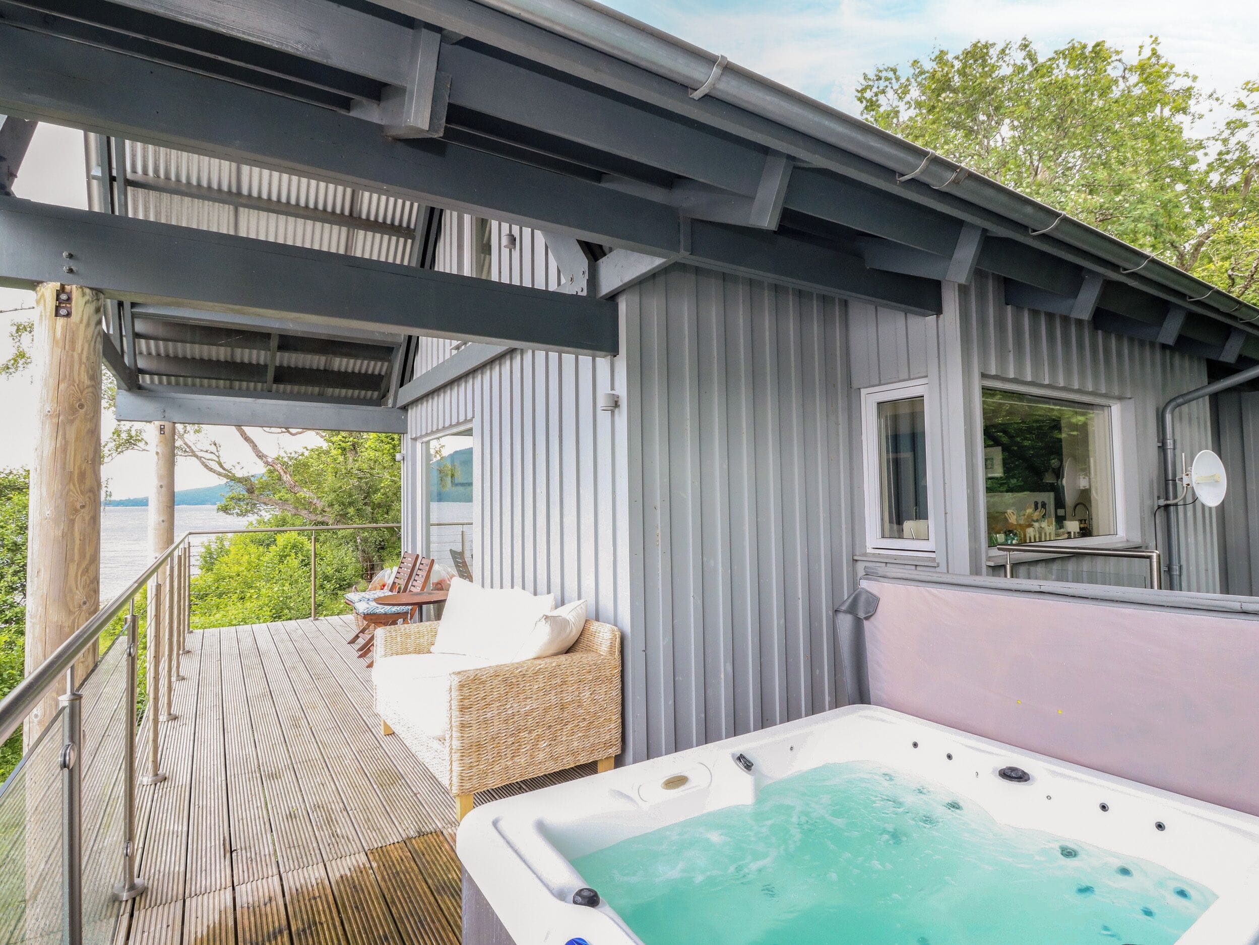 Un espacio al aire libre techado con un jacuzzi, asientos y vista al agua.