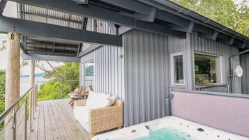 Un espacio al aire libre techado con un jacuzzi, asientos y vista al agua.