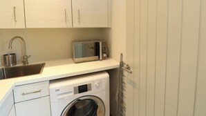 A compact kitchen with a washing machine, a microwave, and a sink.