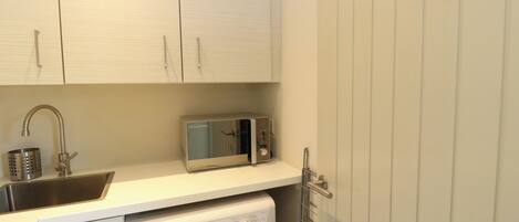 A compact kitchen with a washing machine, a microwave, and a sink.