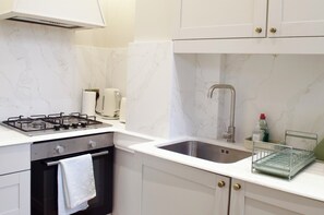 Eine Küche mit Gasherd, Backofen, Spüle und Marmor-Spritzschutz.