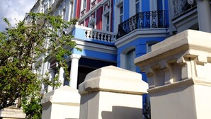 A row of multi-story buildings with classical architecture, featuring columns and decorative moldings. - Notting Hill's Iconic Pink Apartment (London)