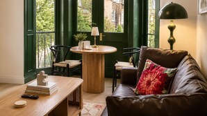A cozy living room with a leather sofa, a wooden coffee table, and a round table with chairs. - Notting Hill's Iconic Pink Apartment (London)
