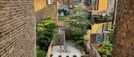 A courtyard with a lawn, a table and chairs, and a shed.
