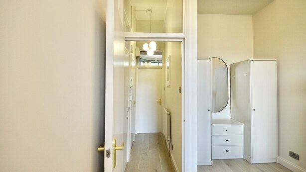 A hallway leading to a room with a vanity and a mirror. - Notting Hill's Iconic Pink Apartment (London)
