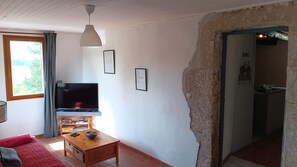 Una sala de estar con televisor, una mesa de centro de madera y un sofá rojo.