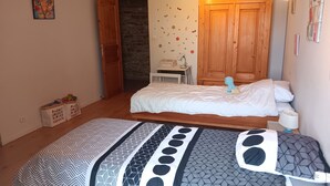 A bedroom with a bed, a nightstand, a lamp, a wardrobe, and a storage box with alphabet letters. - A spacious vacation rental in the countryside with a magnificent view of the Muse Valley. (Saint-Beauzély)