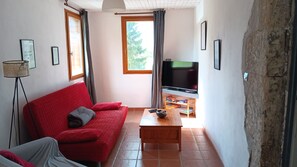 A living room with a red sofa, a wooden coffee table, a television, and a floor lamp. - A spacious vacation rental in the countryside with a magnificent view of the Muse Valley. (Saint-Beauzély)