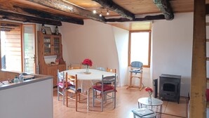 A dining area with a round table, chairs, and a vase of flowers. - A spacious vacation rental in the countryside with a magnificent view of the Muse Valley. (Saint-Beauzély)