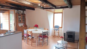 A dining area with a round table, chairs, and a vase of flowers. - A spacious vacation rental in the countryside with a magnificent view of the Muse Valley. (Saint-Beauzély)