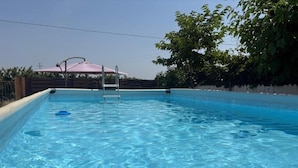 En swimmingpool med en stege, omgiven av ett trästaket och träd.