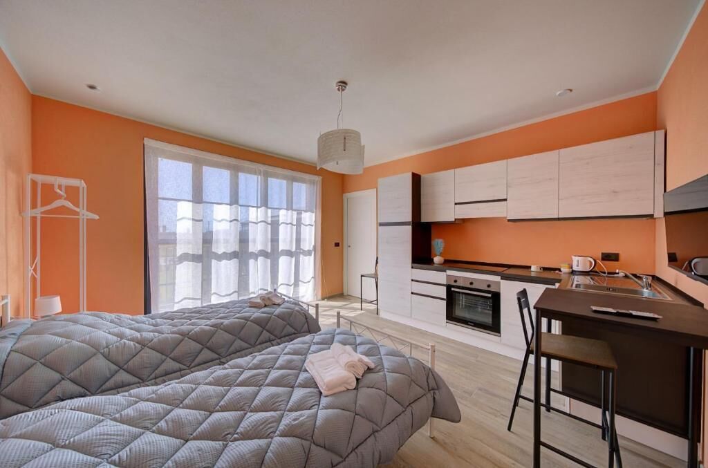 Un dormitorio moderno con una cama grande y una pequeña cocina.