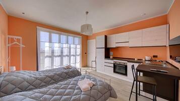 Un dormitorio moderno con una cama grande y una pequeña cocina.