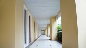 Un lungo corridoio con porte su un lato e finestre sull'altro, che conduce a un edificio.