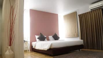 Quarto com cama, mesa de cabeceira, um vaso e janela com cortinas.