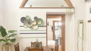 A dining area with a wooden table and chairs, a decorative wall with circular plates, and a tiled floor. - PILLYHOUSE VUCCIRIA: a charming apartment at the entrance to the Vucciria Market (Palermo)