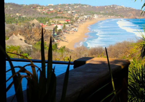 A coastal view with a beach, ocean, and a town in the background.
