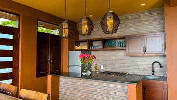 Una cocina moderna con una isla central, luces colgantes y un horno empotrado.