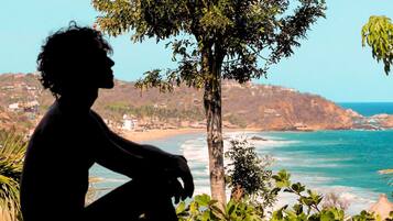 Una persona sentada junto a una piscina con vistas a una playa y al océano.