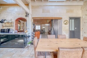 A spacious living area with a wooden dining table, leather chairs, a brick archway, and a stone wall. - Exceptional House with Private Pool Bordeaux (Bordeaux)