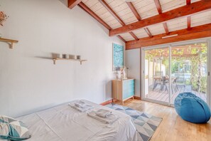 A bedroom with a bed, a nightstand, a wooden shelf, a window, and a view of an outdoor patio. - Exceptional House with Private Pool Bordeaux (Bordeaux)