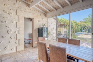 A room with a stone wall, a wooden ceiling, a large window, and a dining table with chairs. - Exceptional House with Private Pool Bordeaux (Bordeaux)