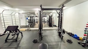 A gym with a squat rack, benches, and weight plates. - SHB Lazer Completo 2min da Praia (Guarujá)