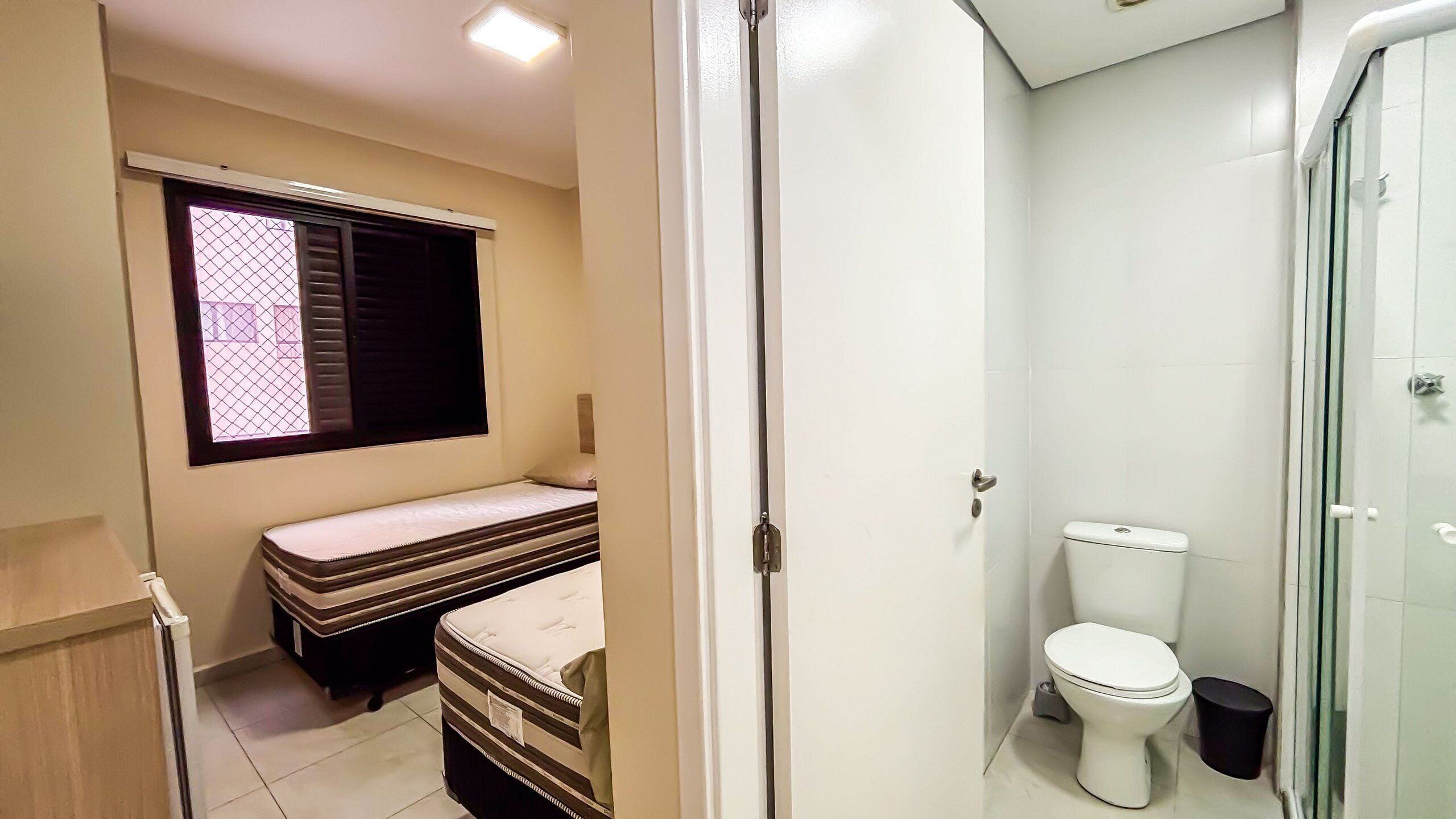 Un baño pequeño con inodoro, ducha y ventana con persianas.