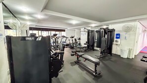 Un gimnasio con diferentes equipos de ejercicio, como cintas de correr, máquinas de pesas y un banco.