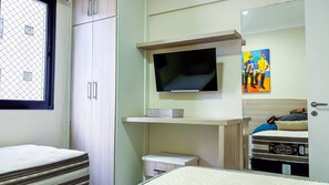 A bedroom with a bed, a TV, a small desk, and a wardrobe. - SHB Lazer Completo 2min da Praia (Guarujá)