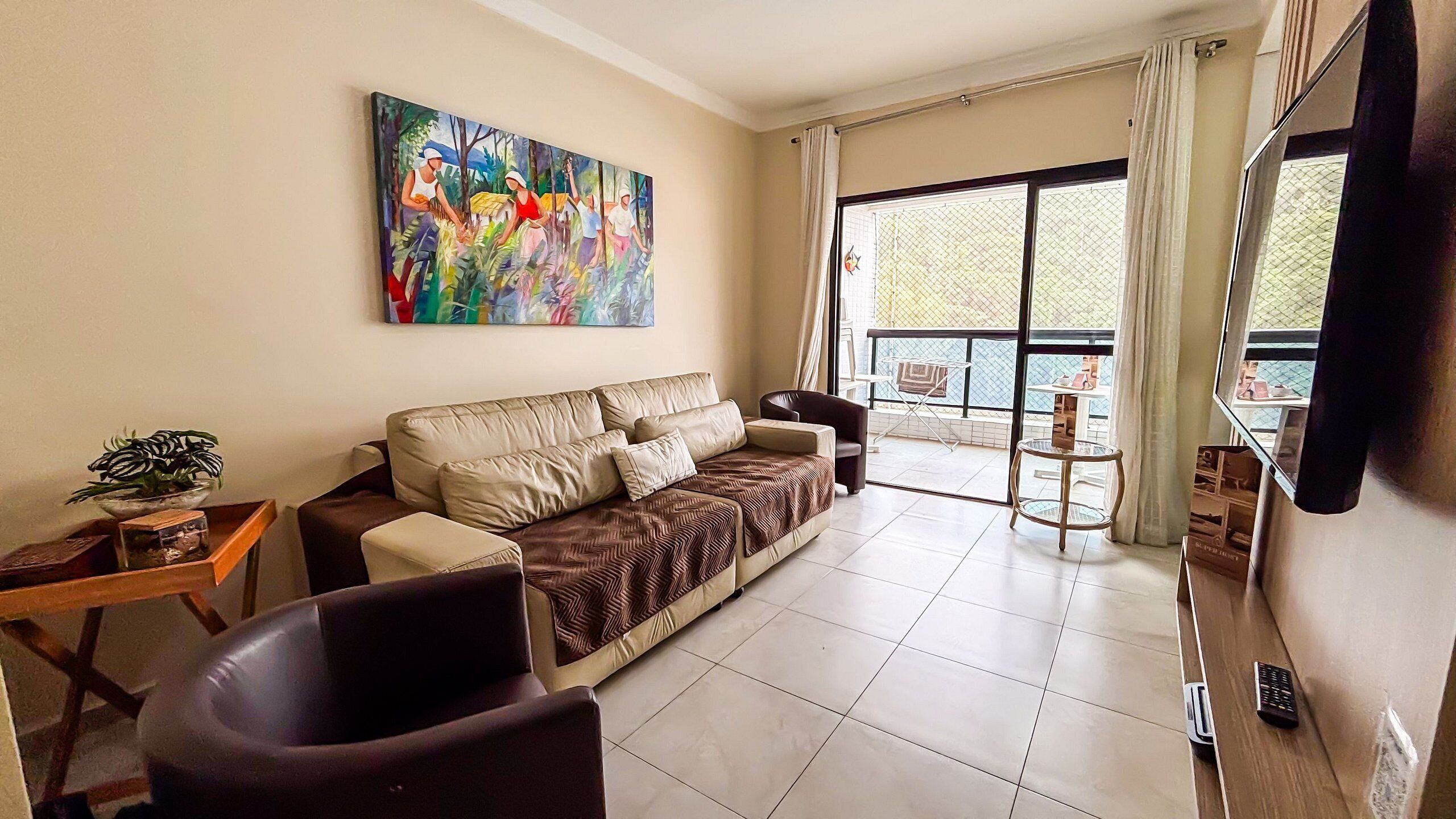 A living room with a sofa, a coffee table, a TV, and a balcony with a view.