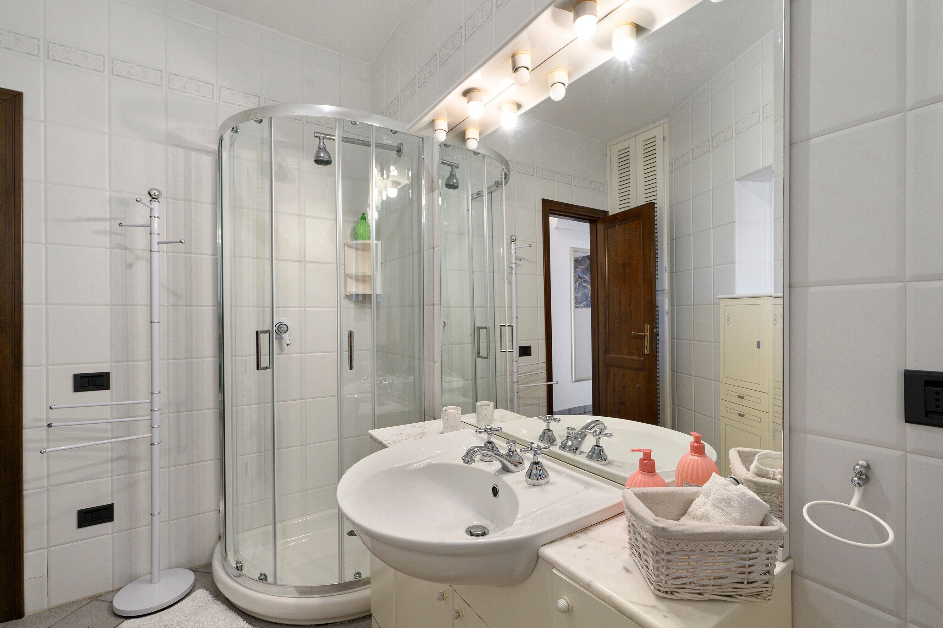 Une salle de bain avec une douche à parois de verre, un lavabo doté de plusieurs robinets et un miroir au-dessus du lavabo.