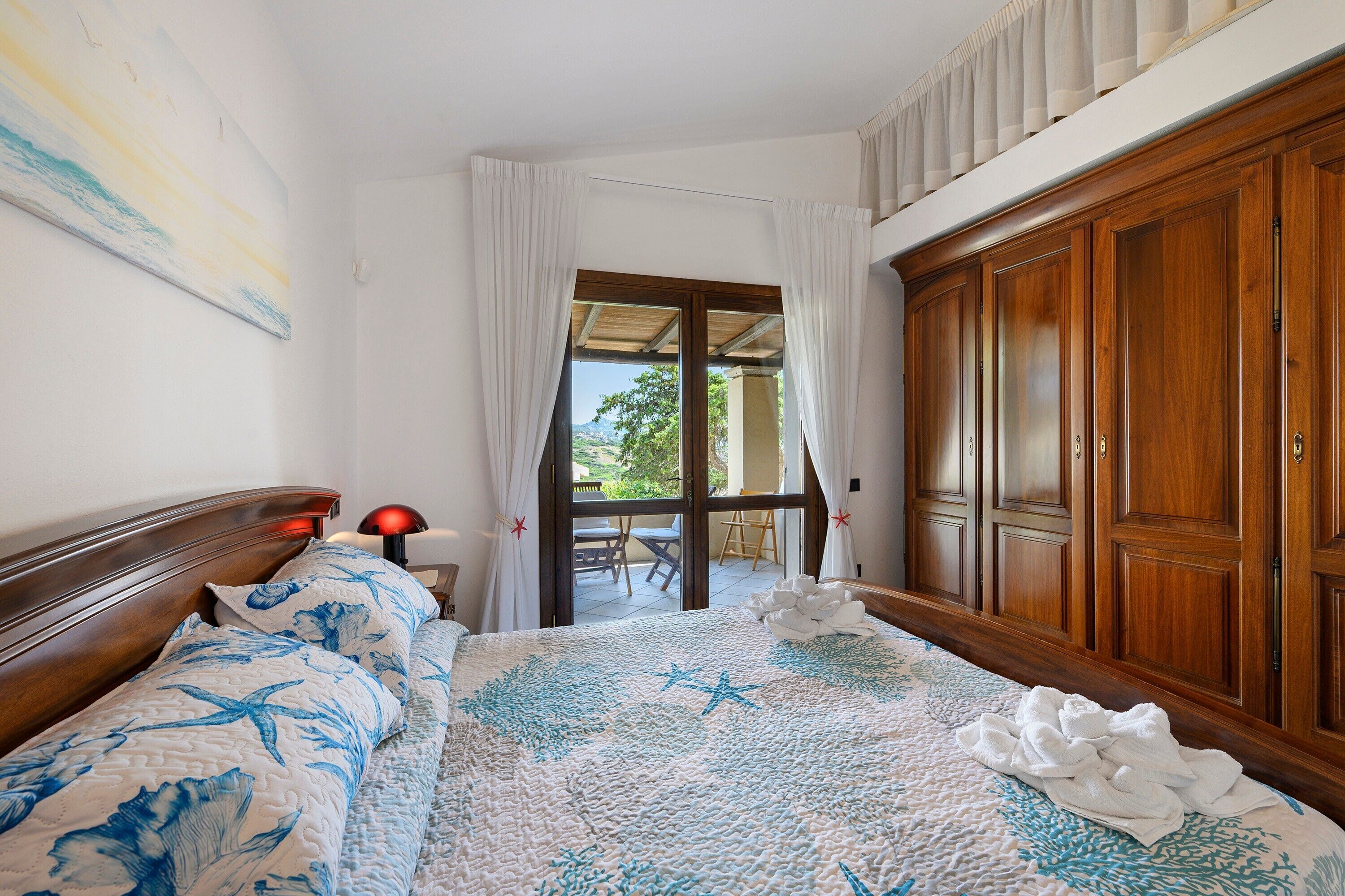 Une chambre d’hôtel avec un lit, une armoire en bois, une fenêtre avec des rideaux et une vue sur l’extérieur.