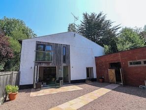 Un bâtiment à deux étages, à l’extérieur blanc, doté d’une façade en lambris de bois et d’une cour recouverte de gravier.