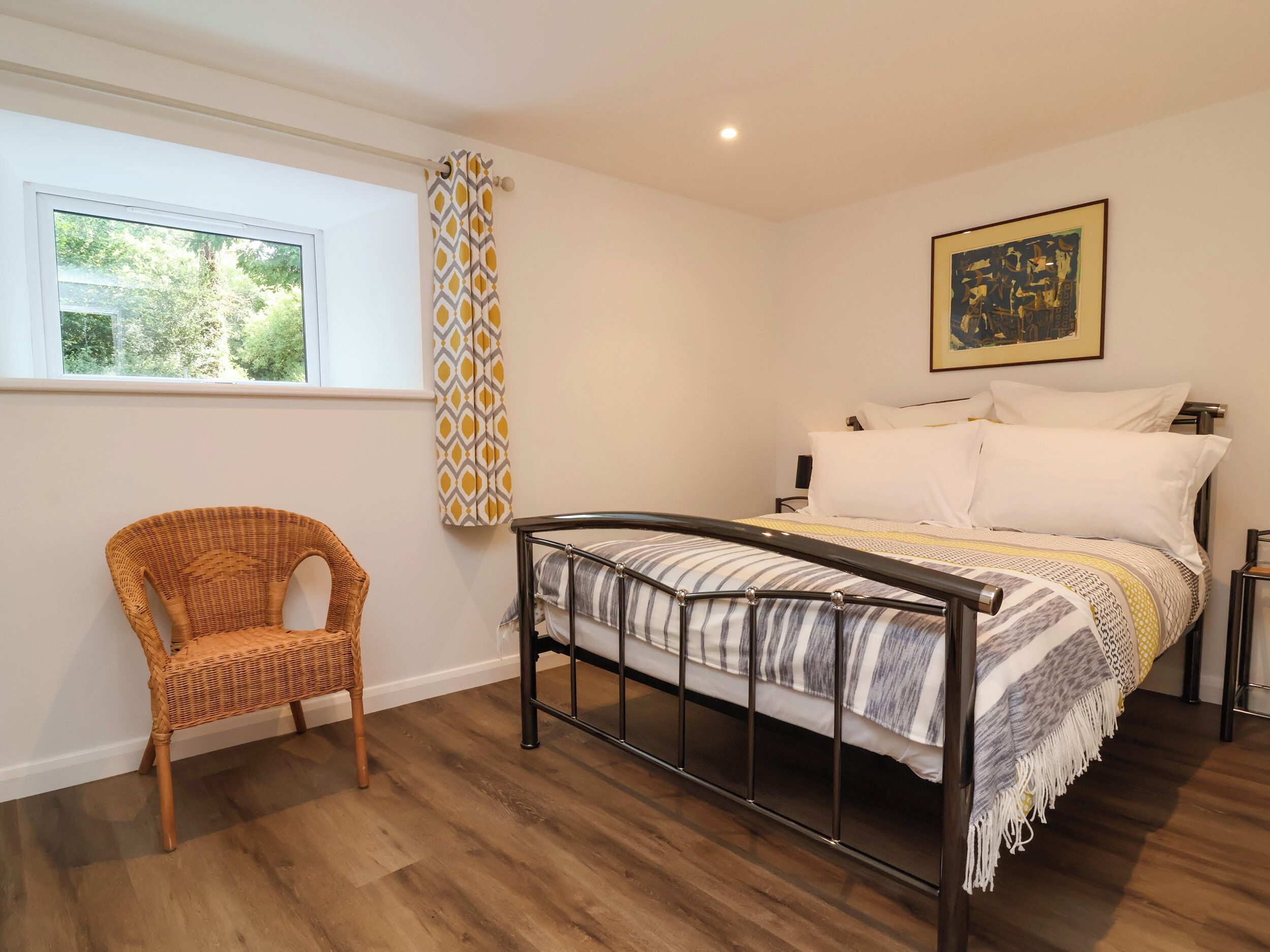Una camera da letto con un letto, una sedia, una finestra e un quadro appeso al muro.