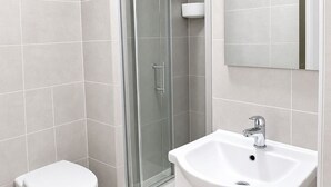 Ein Badezimmer mit Toilette, Waschbecken und einer Duschkabine aus Glas.