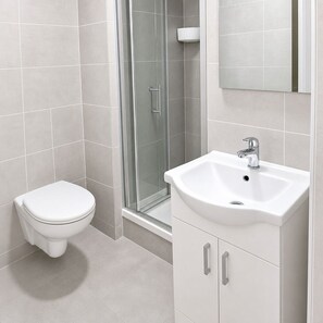 A bathroom with a toilet, a sink, and a glass shower enclosure. - Modern Central Dublin Apartment Near Bolton Square (Dublin)