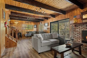 A wooden interior with a fireplace, a sofa, and a dining area. - Quiet Mountain Cabin Escape (Lake Arrowhead)