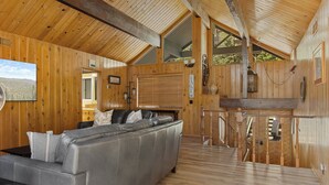 Un interno accogliente con divano, pareti in legno, angolo cottura e vista sull'esterno.