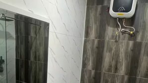 Un baño con zona de ducha, un espejo y un panel de control en la pared.