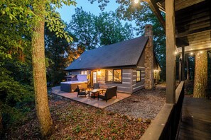 A cabin with a stone exterior, a hot tub, and a patio with outdoor seating. - Modern 2-bedroom cabin with Hot Tub in charming Pigeon Forge (Pigeon Forge)