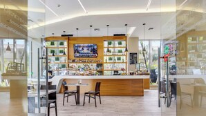 A bar area with a wooden counter, seating, and a TV screen. - Beachwalk Studio Resort-Style Amenities (Hallandale Beach)