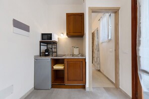 Eine kompakte Küche mit eingebauter Mikrowelle, einem kleinen Kühlschrank und Holzschränken.