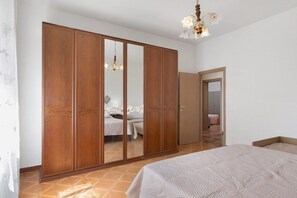A bedroom with a large wardrobe, a bed, and a chandelier. - Apartment 'Cielo' with Shared Garden, Wi-Fi and Air Conditioning (Volterra)