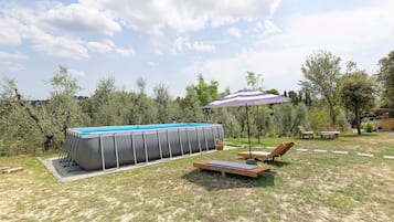 A backyard with a rectangular swimming pool, lounge chairs, and a patio table.