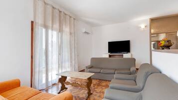 A living room with a sofa, a television, and a coffee table.
