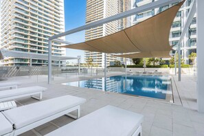 A rooftop swimming pool with sun loungers and a shaded area. - StayShort | Stunning Beachfront 2-Bedroom Apartment Sleeps 6 with Infinity Pool, Skyline Views & Private Beach Access (Dubai)