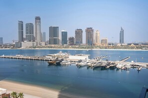 A marina with boats docked, a waterfront view, and a city skyline with high-rise buildings. - StayShort | Stunning Beachfront 2-Bedroom Apartment Sleeps 6 with Infinity Pool, Skyline Views & Private Beach Access (Dubai)